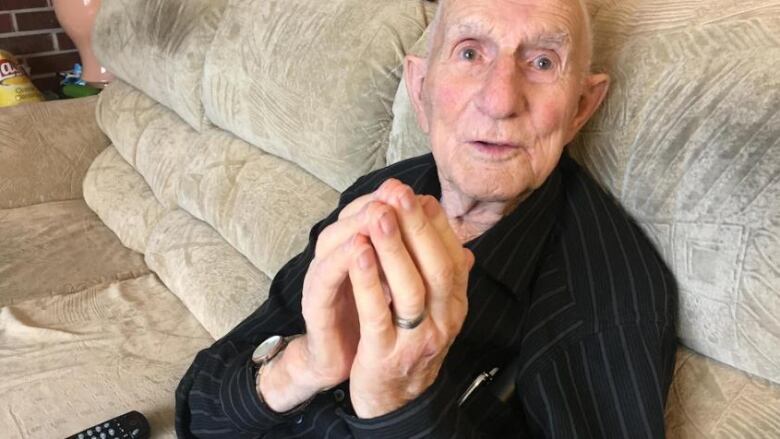 An elderly man sitting on a sofa.