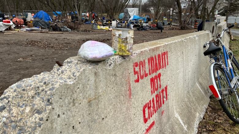 Tents and tarps can been seen being a cement barrier with the words 