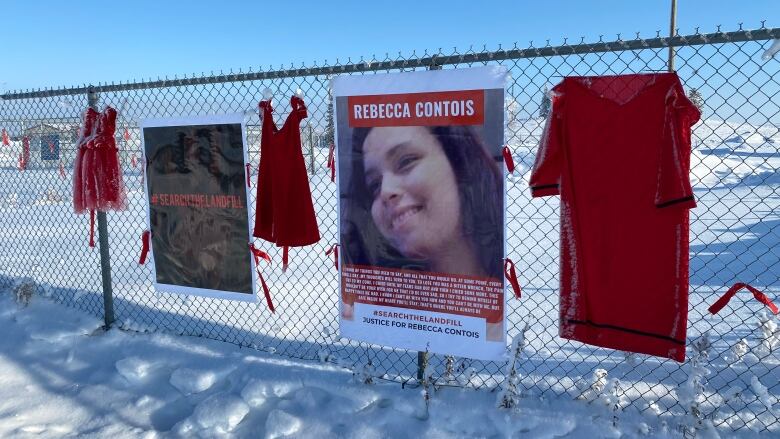 Signs and red dresses hang on a fence outside a landfill south of Winnipeg.