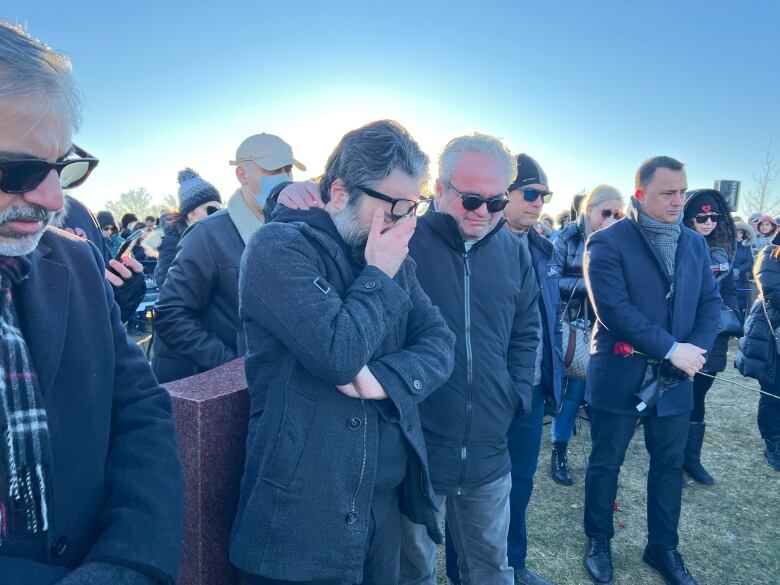 Hamed Esmaeilion is comforted on Jan. 7, 2023, at the Richmond Hill gravesite of his nine-year-old daughter, Reera, and wife, Parisa Eghbalian, who both died when Flight PS752 was shot down on Jan. 8, 2020.