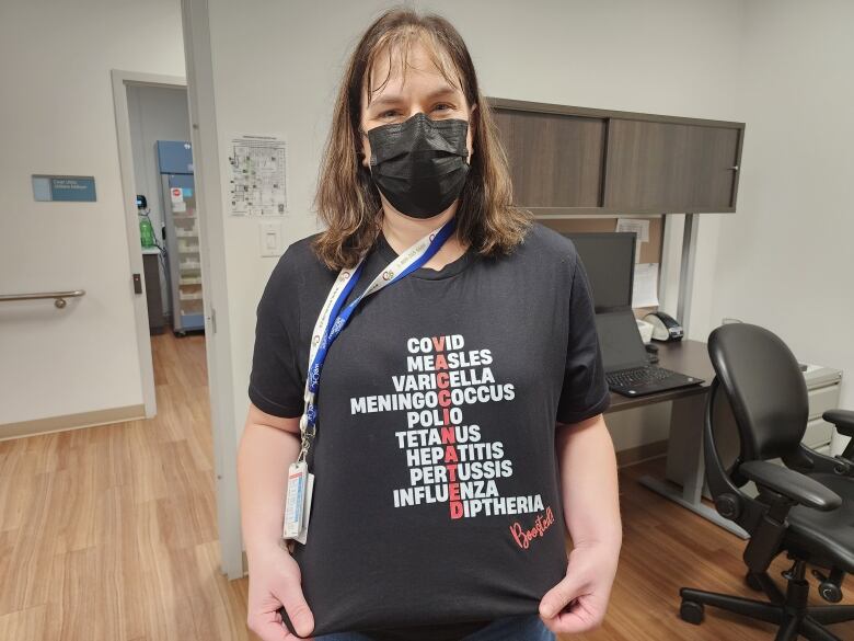 A women wearing a face mask and a black t-shirt which shows all the vaccination she has received