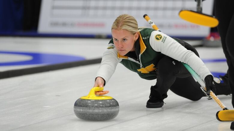 A woman delivers a curling rock.