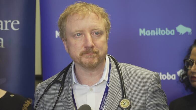 A man stands at the podium with a stethoscope around his neck.