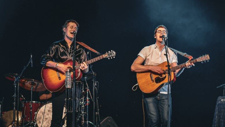 Two musicians  a father-son duo  playing guitar and singing on stage.