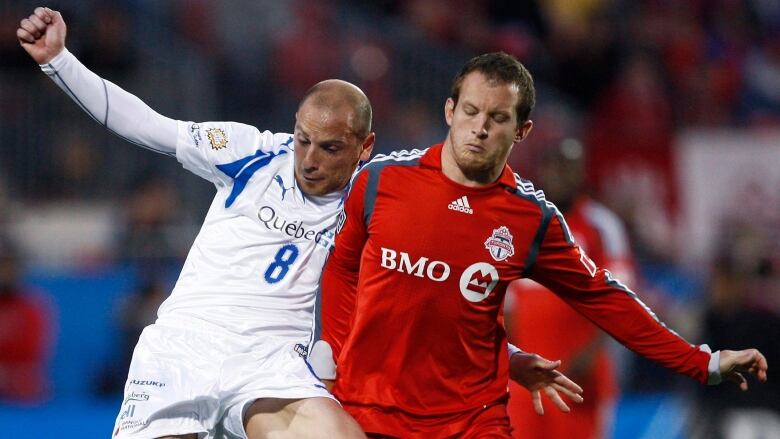 Two men going after a soccer ball.