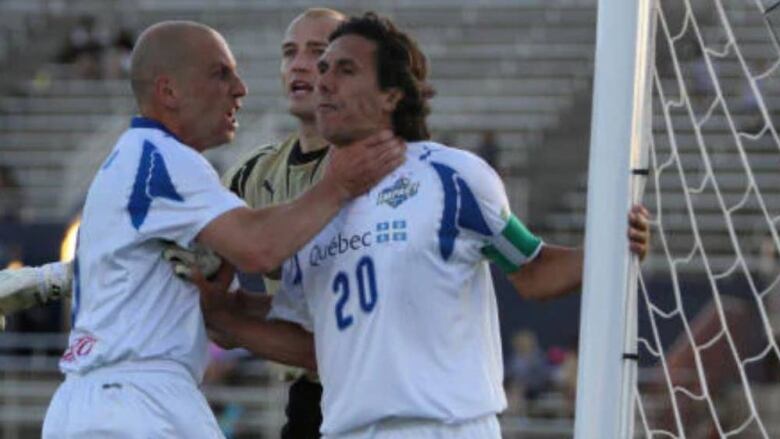 A soccer player grabbing another by the throat. 