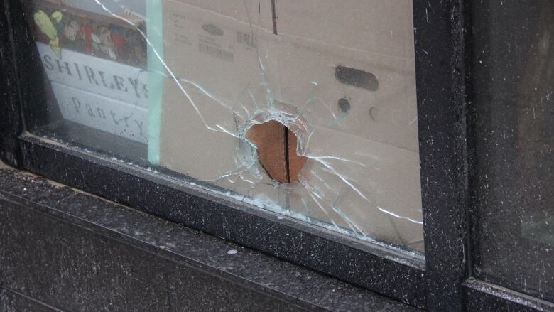 A broken window with cardboard behind it.