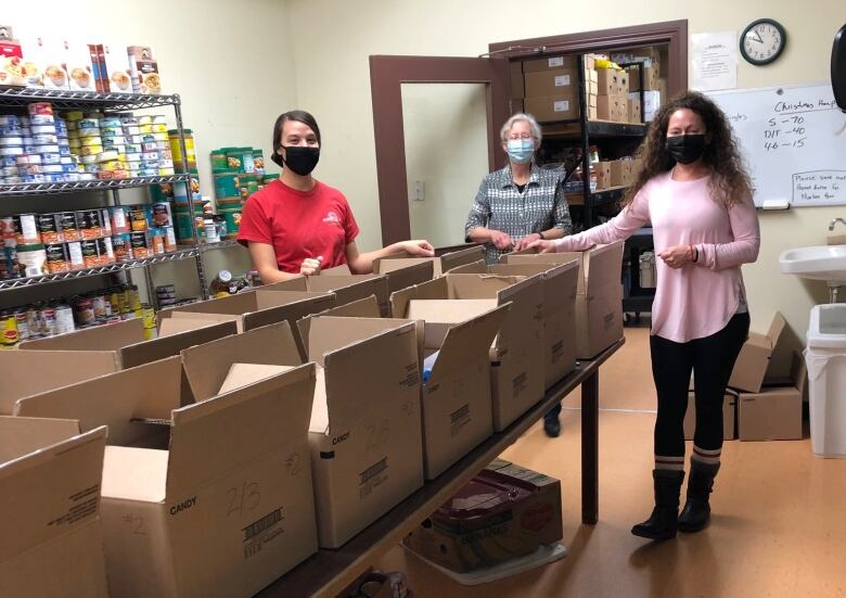 A photo of three volunteers filling boxes at the Dryden Food Bank. More than 40 volunteers work at the food bank, which distributed nearly 5,400 hampers in 2022.