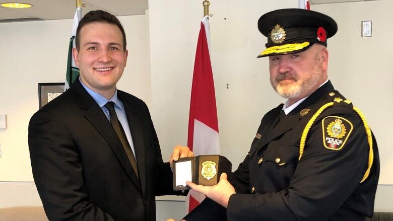 A police constable is pictured smiling as he accepts his badge from the chief of the Nelson Police Department.