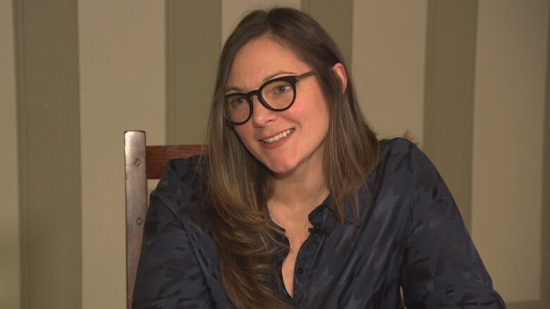 A woman sitting in a chair, smiles.