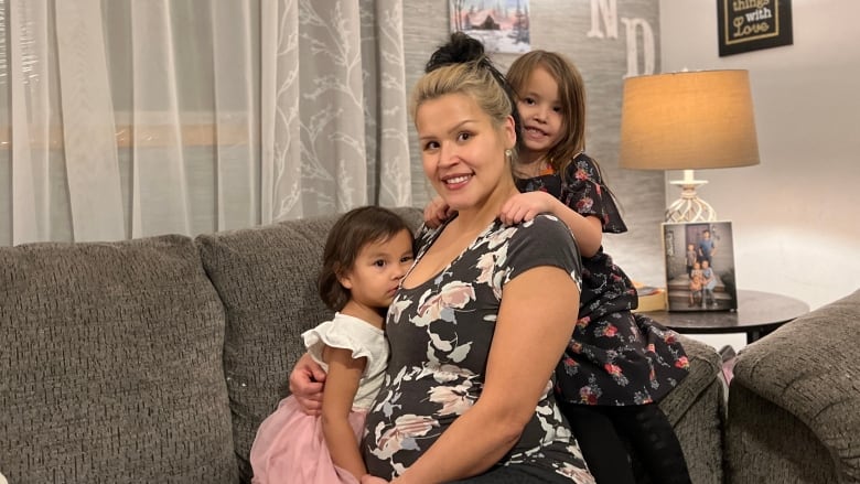 Happy mother with two young girls on a couch. 