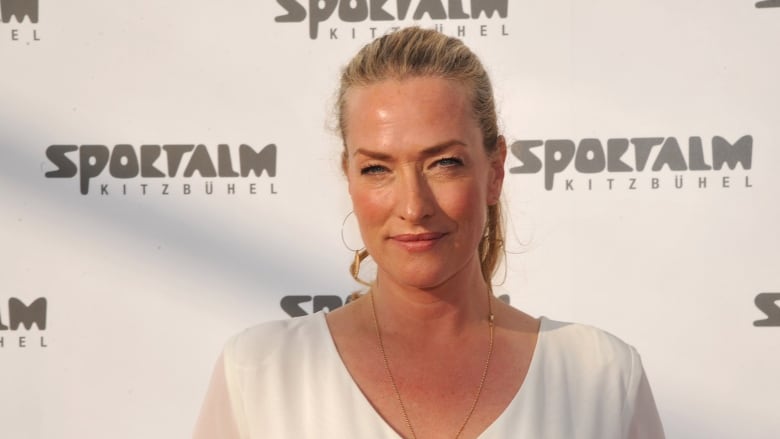 A blonde woman wearing white poses for the camera.