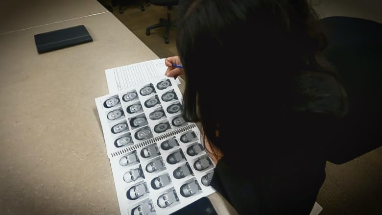 A girl looks at a catalogue of faces.