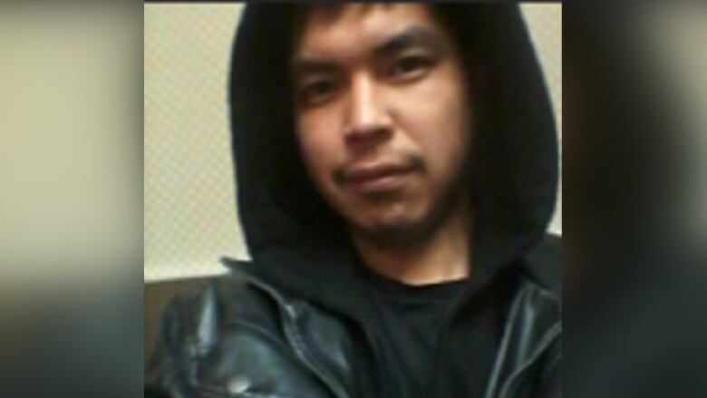 A man in a black T-shirt and black hoodie.