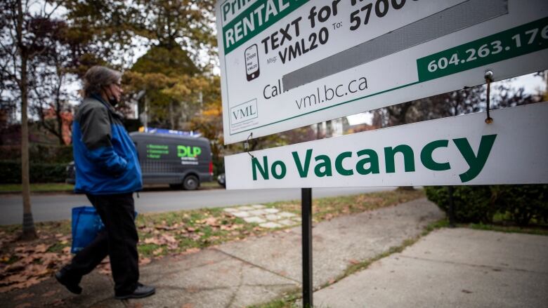 A person walks past a 'no vacancy' sign.