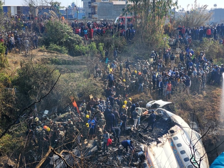 Several people surround a plane's wreckage.