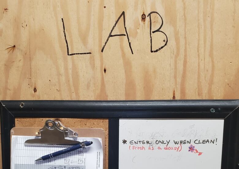 The front door of the lab for growing mushrooms indoors at Windy Heights Farm. On a whiteboard is written 