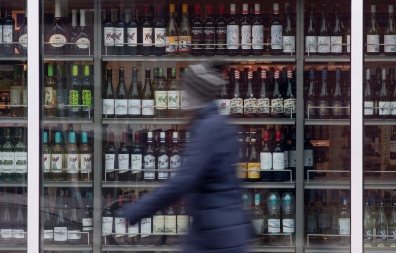 A person walks past shelves of bottles of alcohol on display.