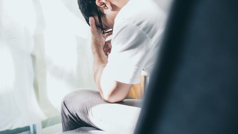 A man sits with his head in his hands.