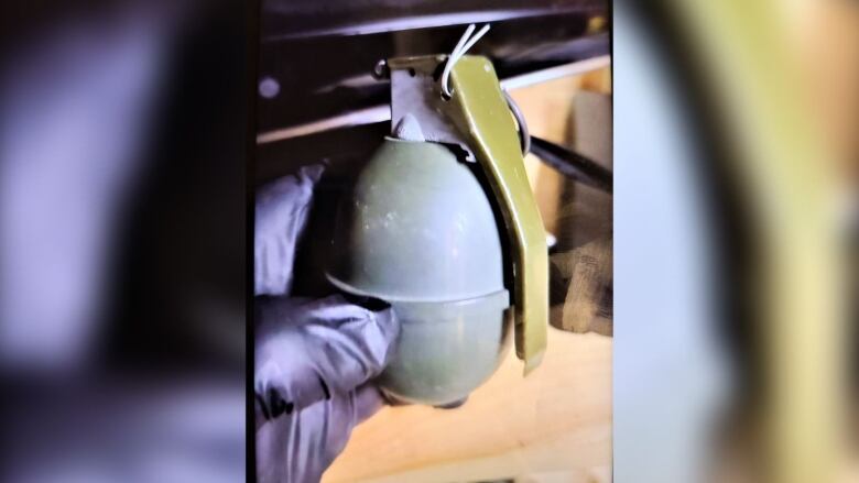 a gloved hand holds a grenade.