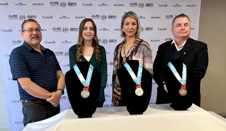 Four people standing together against a wall.