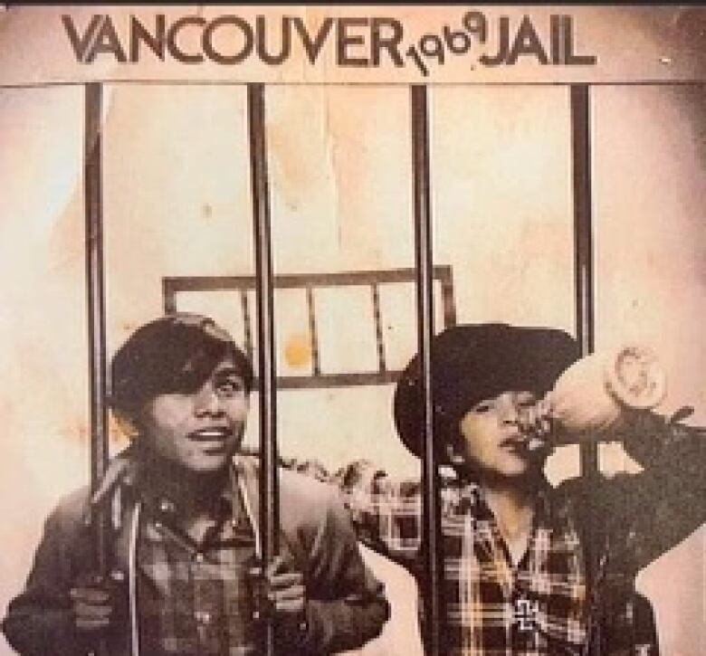 Two children pretend to be in behind bars with a sign above them that read, 