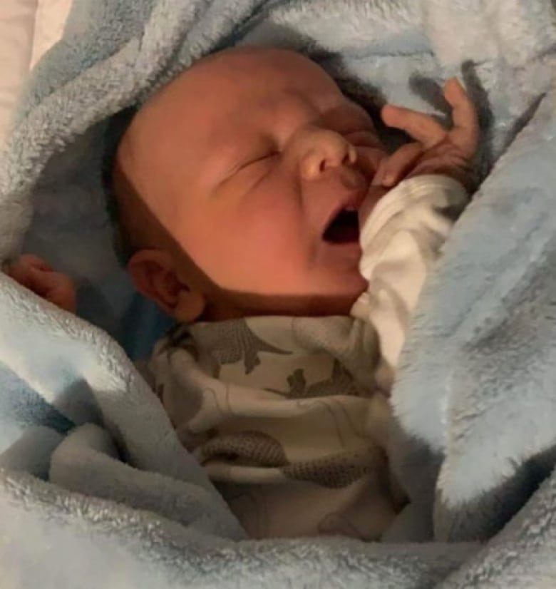 A newborn baby is pictured wrapped in a blue blanket.