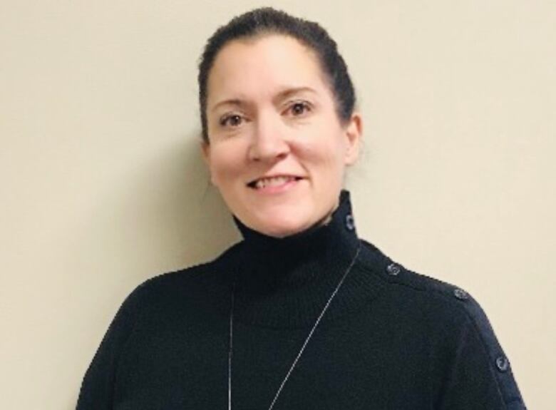 A woman with a dark shirt and sweater smiles.