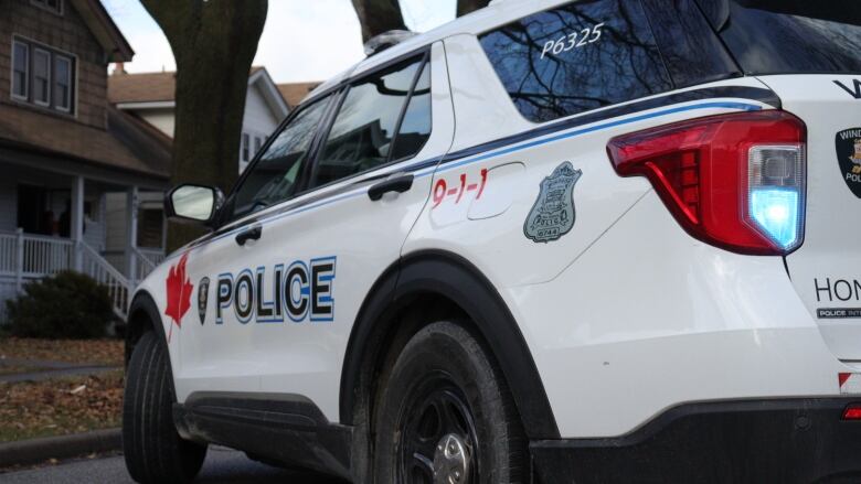 A white SUV with Windsor police logo on it is parked in the middle of a street.