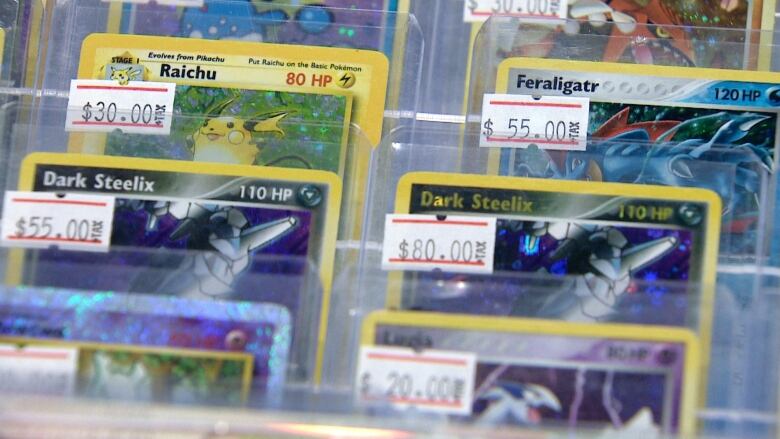 Pokemon cards line the shelf of a glass case.