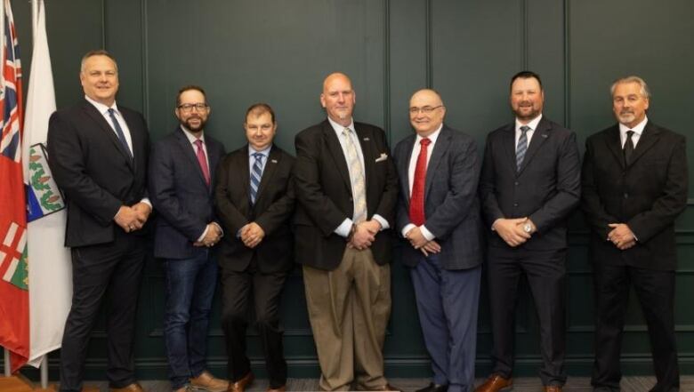 Seven male politicians stand in a row.