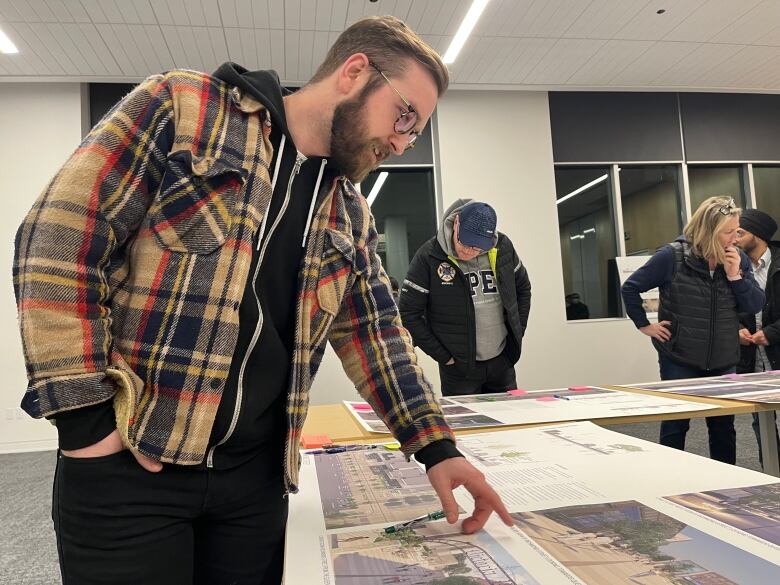 Man in a plaid coat looks at a photo on a desk.