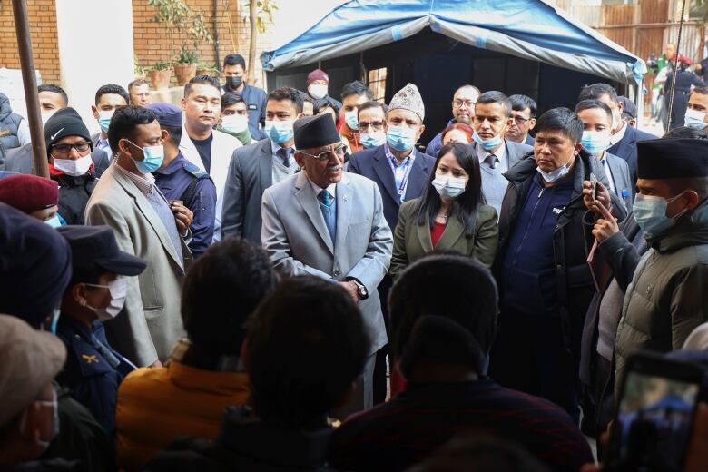 A man speaks while encircled by a large gathering of people in an outdoor setting.