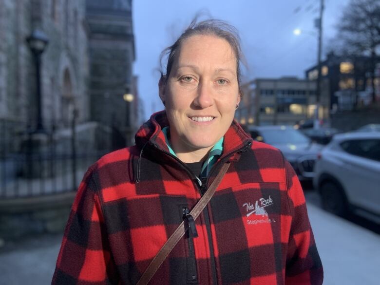 A person in a red flannel stands outside a stone building at twilight.