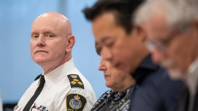 Adam Palmer, the chief of the Vancouver Police Department, looks over to Mayor Ken Sim and other officials.