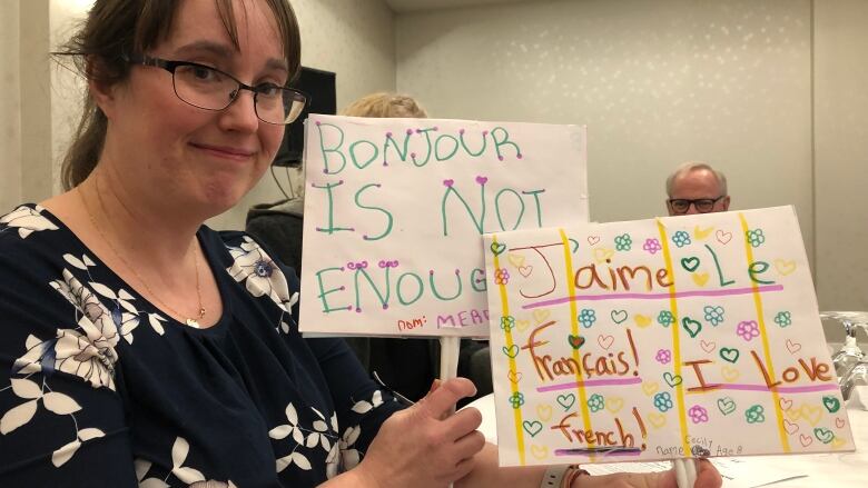 A woman holds up two home made signs.