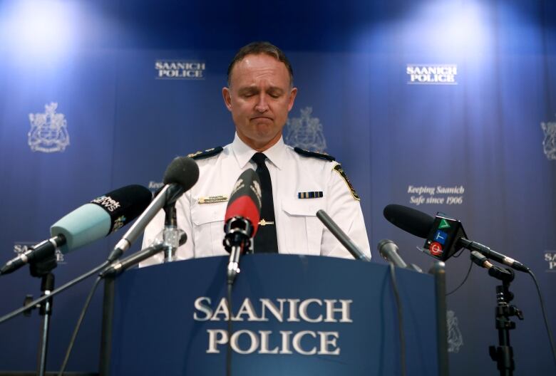 Saanich Police Chief Dean Duthie stands behind a podium marked 