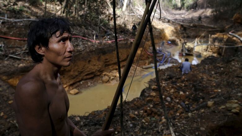 A man stands near a gold mine.