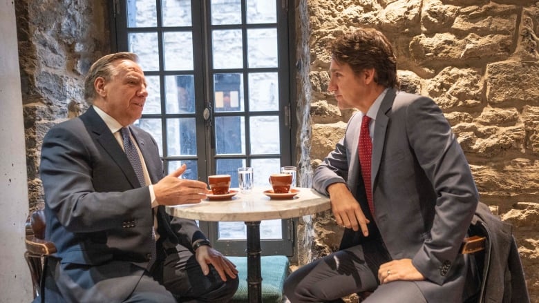 Two men sit across from each other at a small table. 