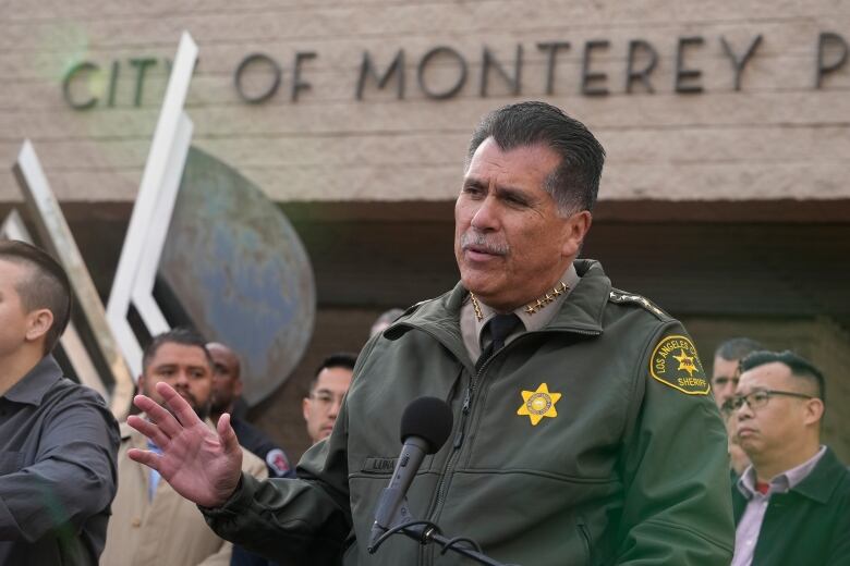 A police official in a green jacket speaks about the investigation. 