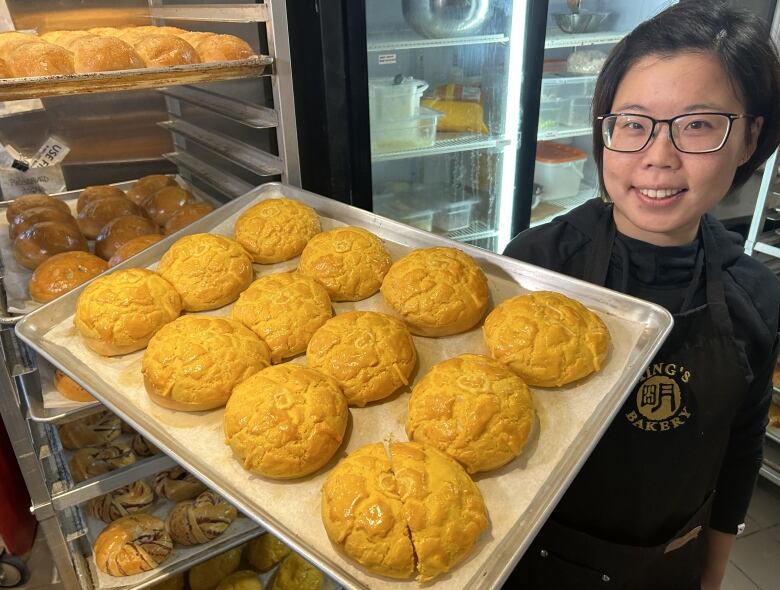 A woman holds up a display of baked goods.