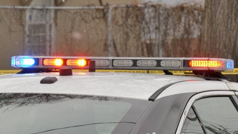 A closeup shows the flashing lights on the roof of a white police car.