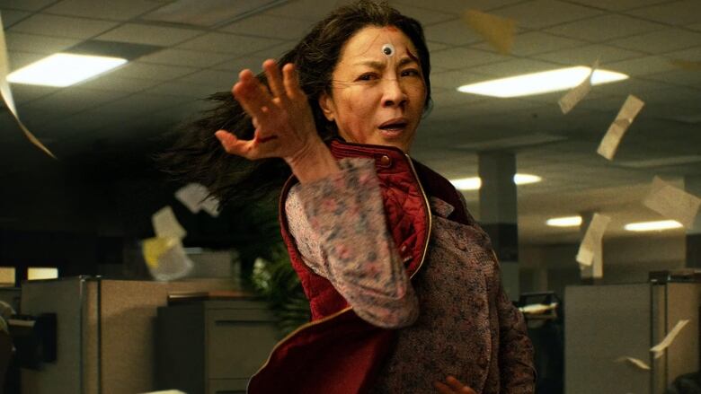 Still frame from Everything Everywhere All At Once. Michelle Yeoh does a martial arts pose with a googly eye stuck to her forehead.