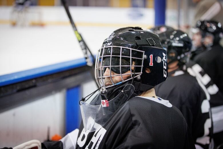 A helmeted hockey player on the bench.