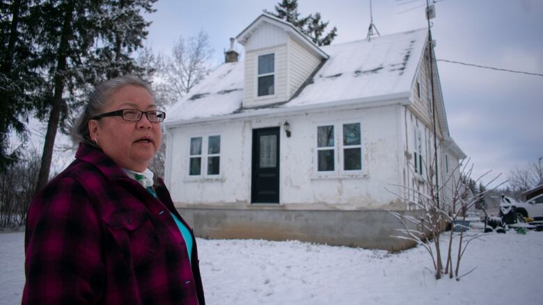 A woman stands in front of a house.