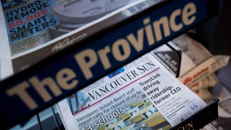 Newspapers are pictured on a newsstand.