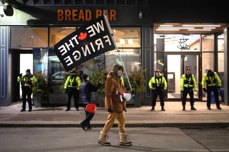 A Hamilton protestor carries a flag that reads 