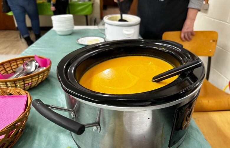 A pot full of soup placed on a table with a green tablecloth.