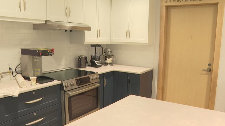 Kitchen with stove, oven, coffee maker, kettle, blender and mixer.