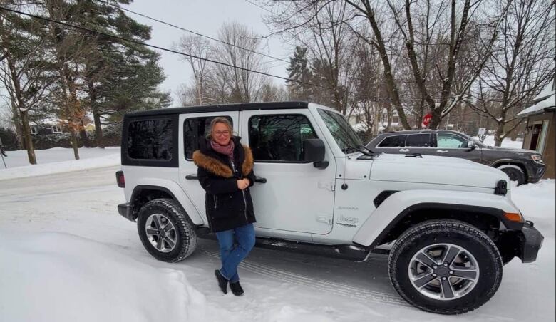 A woman standing in front of her car